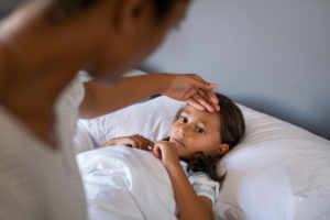Mother checking on her sick child in bed