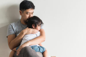 A father holding his sick child before taking them to see a pediatrician.