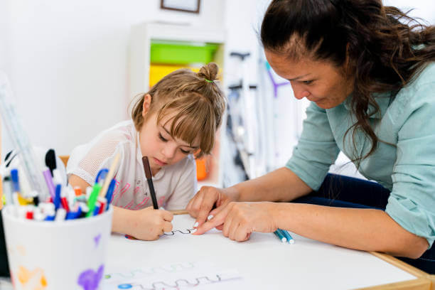 A girl with down syndrome is in a classroom with her teacher