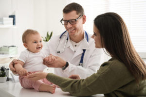 Mother with her cute baby visiting pediatrician in clinic fro wellness checkup