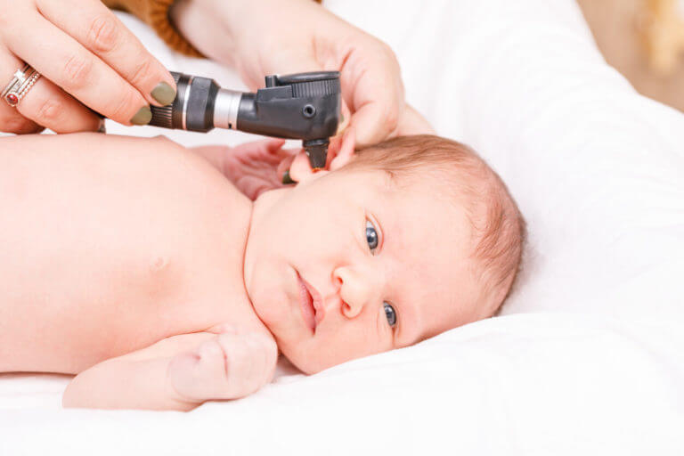 During a newborn ENT exam, a doctor checks the ears of an infant with an otoscope for signs of ear infection in a pediatric clinic.